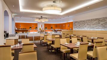 A modern restaurant with a central bar, booths, and a stone accent wall.