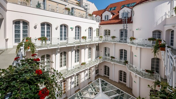 Un edificio de varios pisos con balcones, ventanas amplias y un patio central con piso de vidrio.