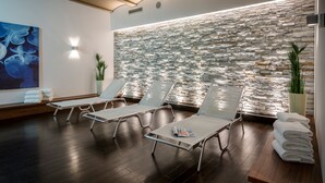 Un cuarto de spa con dos sillones de vidrio, una pared de piedra y un cuadro abstracto de gran tamaño.