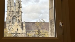 A window view of a historic building with intricate architecture, including a large arched window and multiple towers. - Hôtel de Caen (Caen)