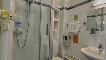 A bathroom with a glass-enclosed shower, a white toilet, a sink, and a mirror above the sink.