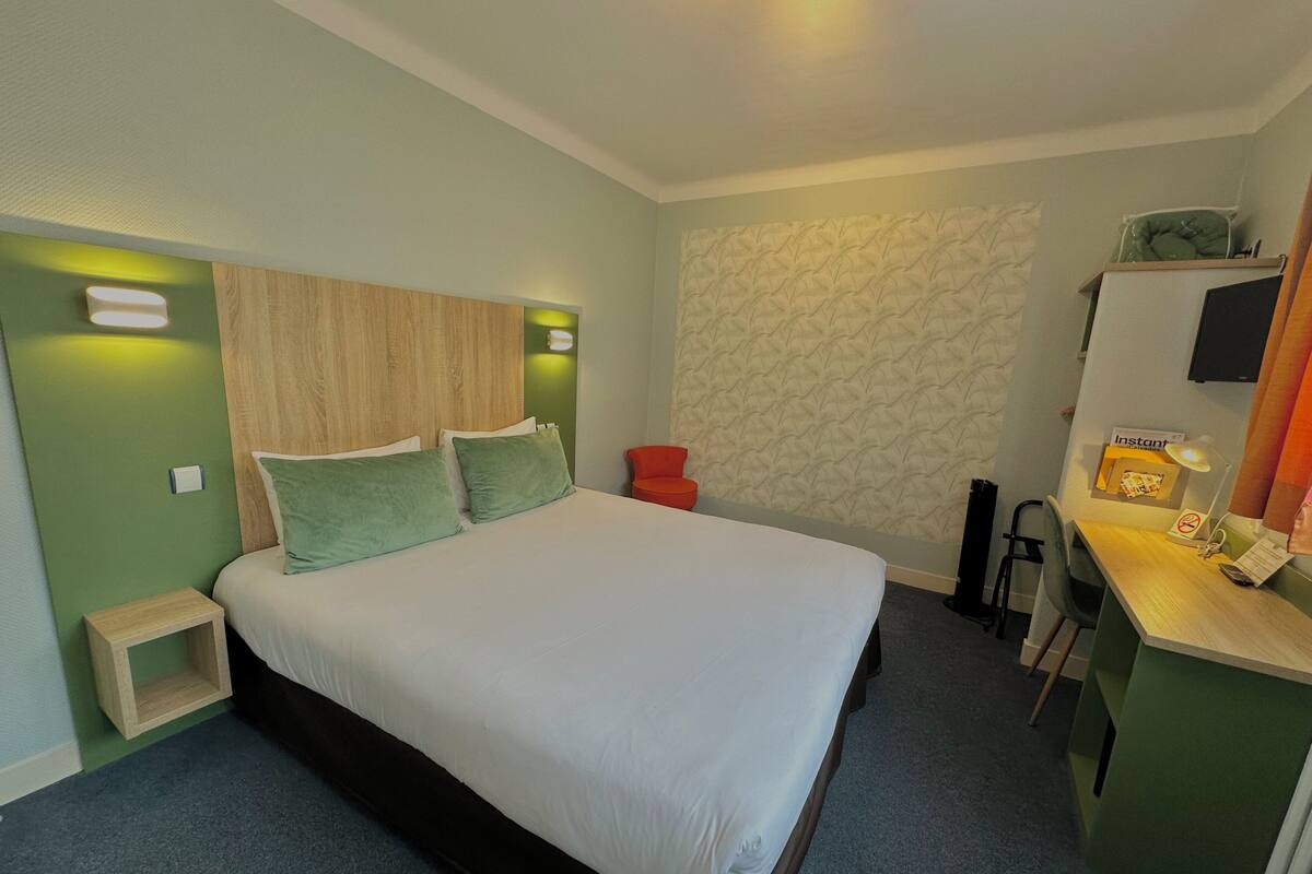 Une chambre d’hôtel bien rangée, avec un lit, un bureau et une chaise.
