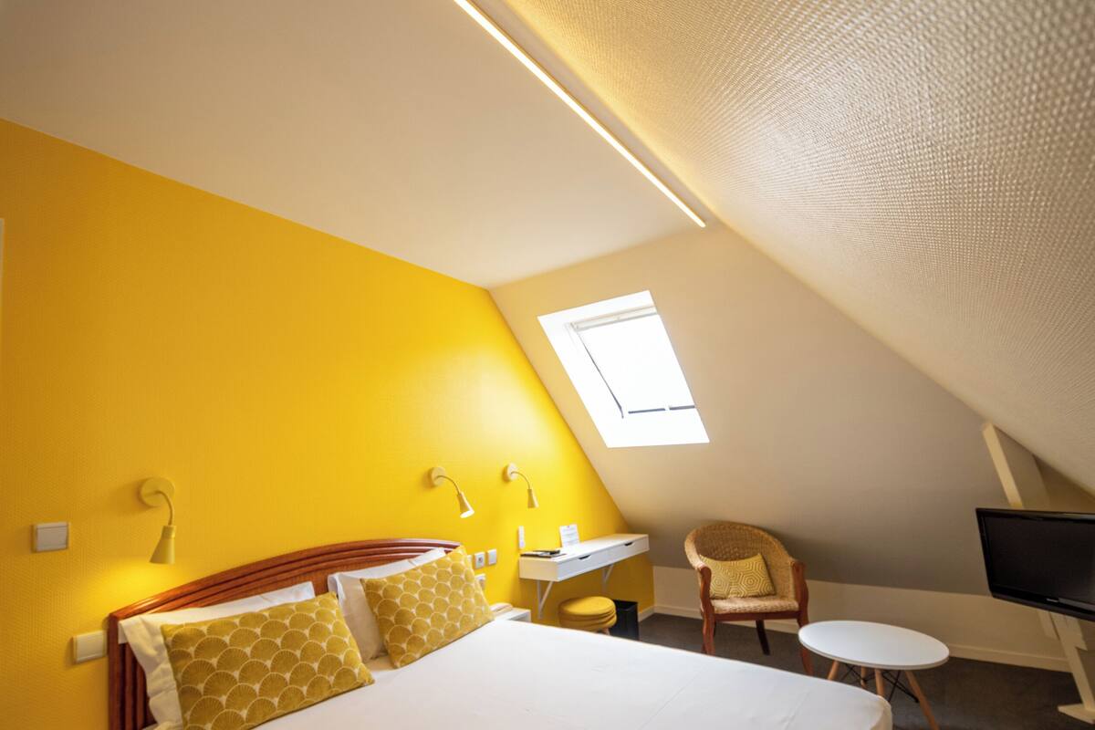 Une chambre d’hôtel avec un lit, un bureau, une chaise et un téléviseur.