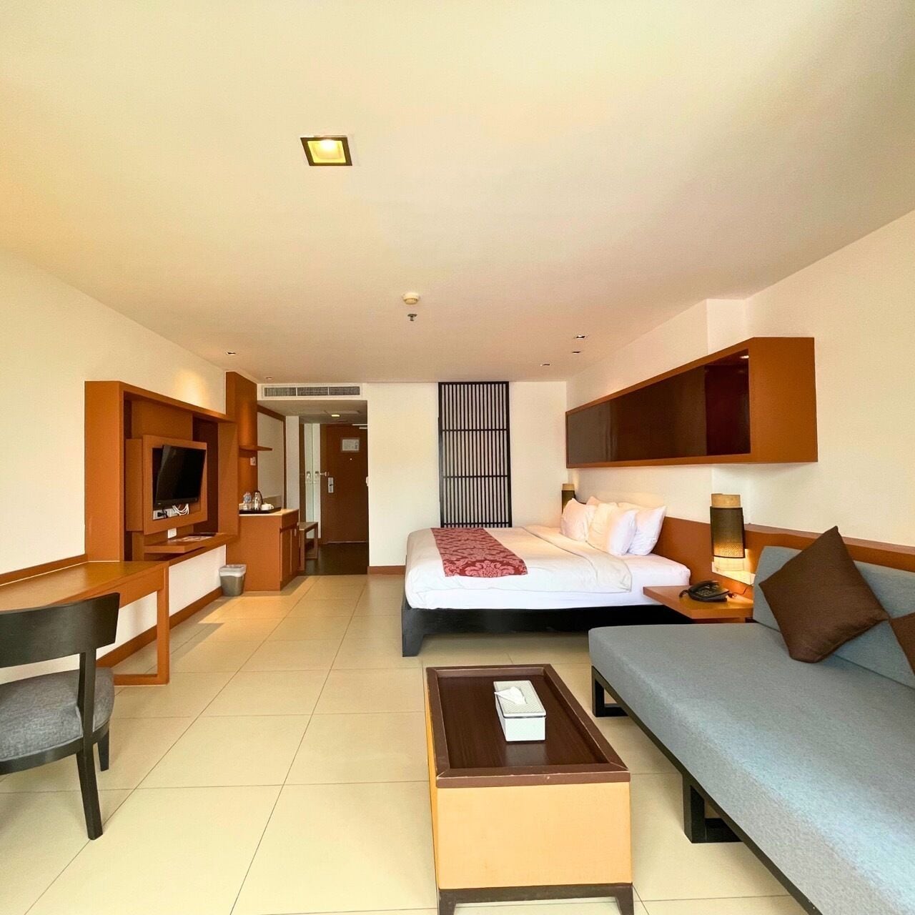 Une chambre d’hôtel comprenant un lit, un canapé, une télévision, un bureau et une table basse.