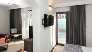 A hotel room with a bed, a desk, a chair, a TV, and a view of the sea. - Beach Hotel Split (Podstrana)