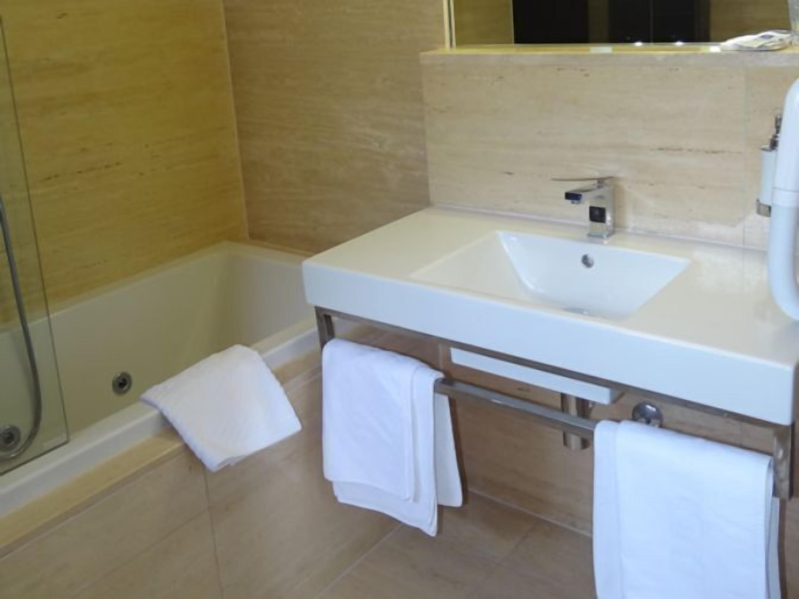 A bathroom with a white sink, a mirror, and a shower area.