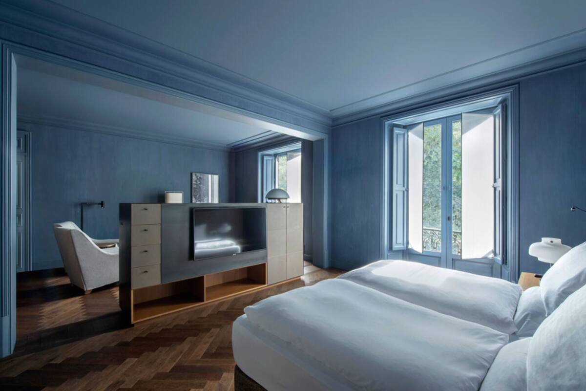 Un dormitorio moderno con una cama grande, un escritorio con televisor y una silla.
