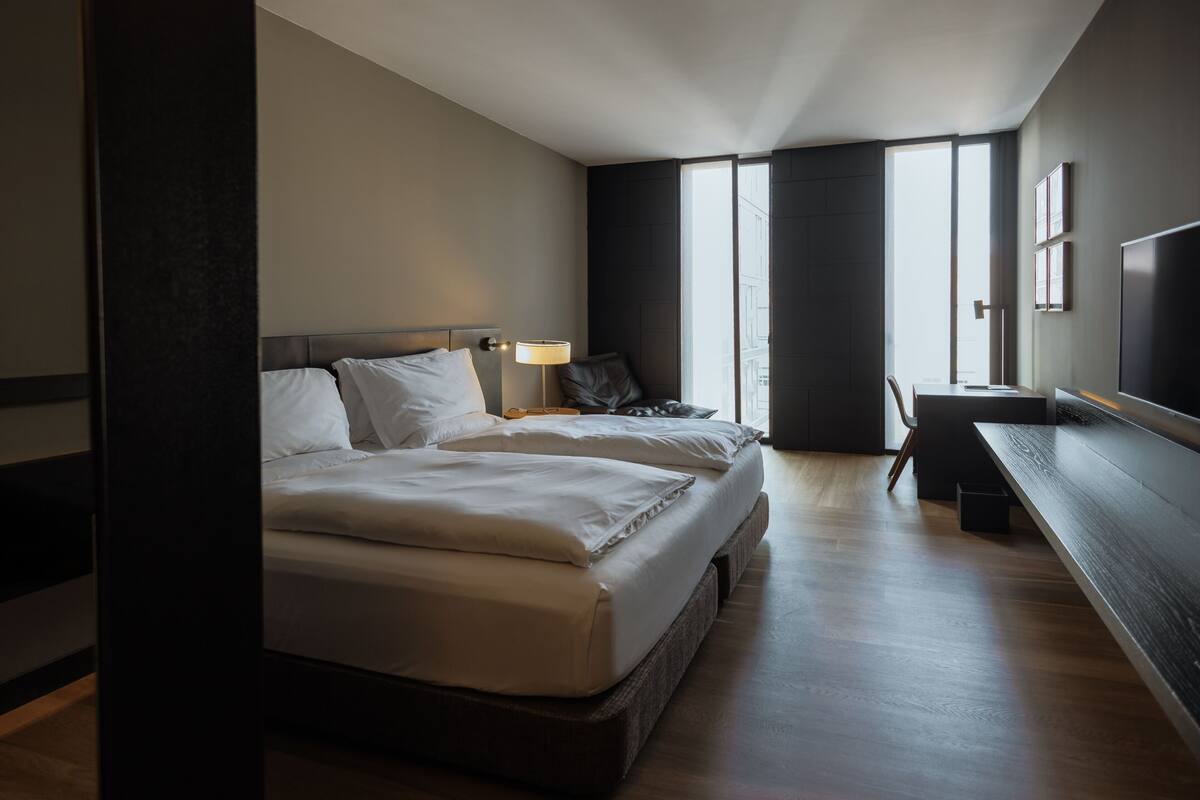 Una habitación de hotel moderna con una cama grande, mesitas de noche, un escritorio y un televisor.