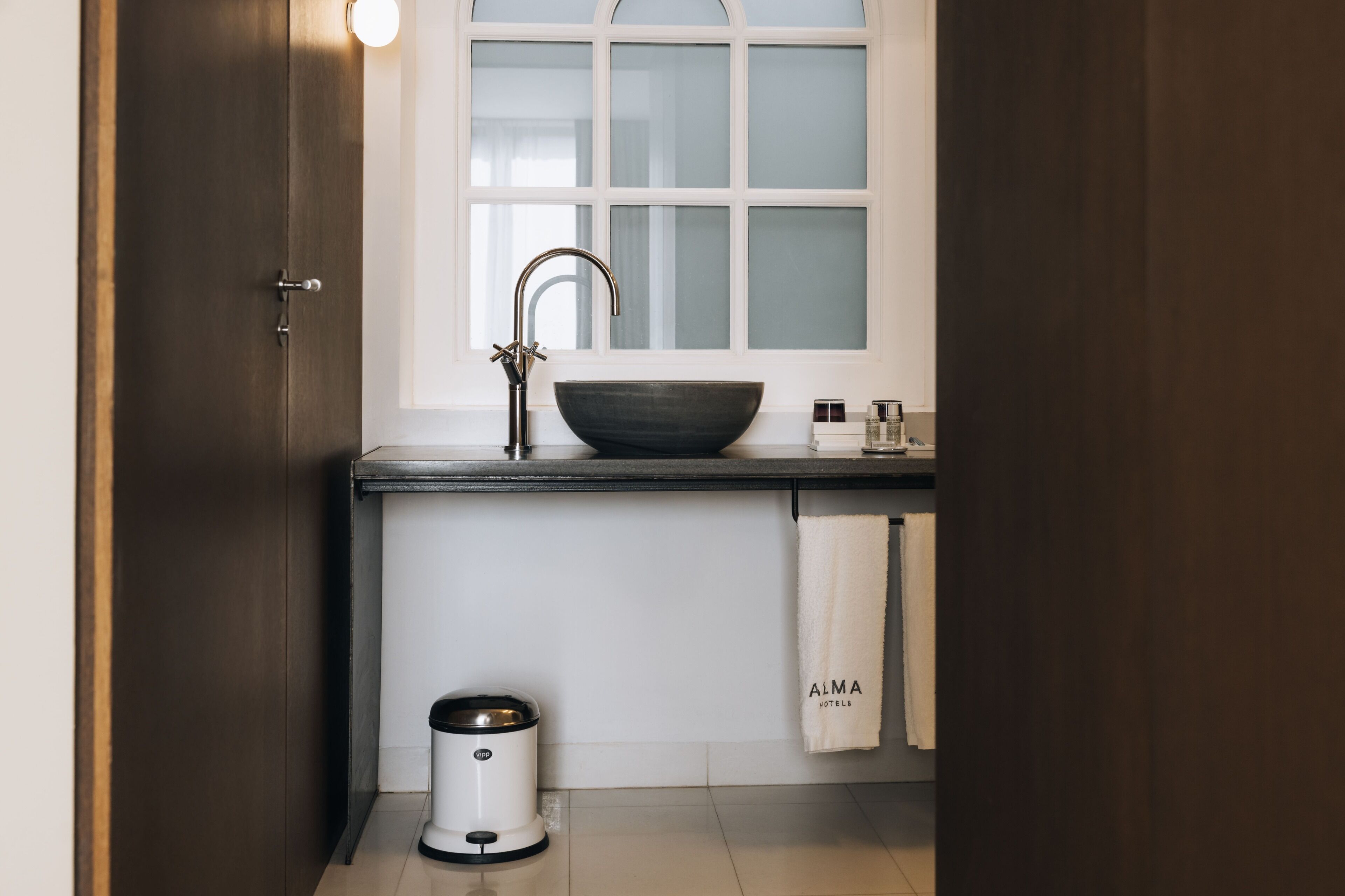 Een moderne keuken met een grote spoelbak, een raam en een prullenbak.