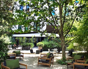 An outdoor seating area with wooden furniture and a large tree.