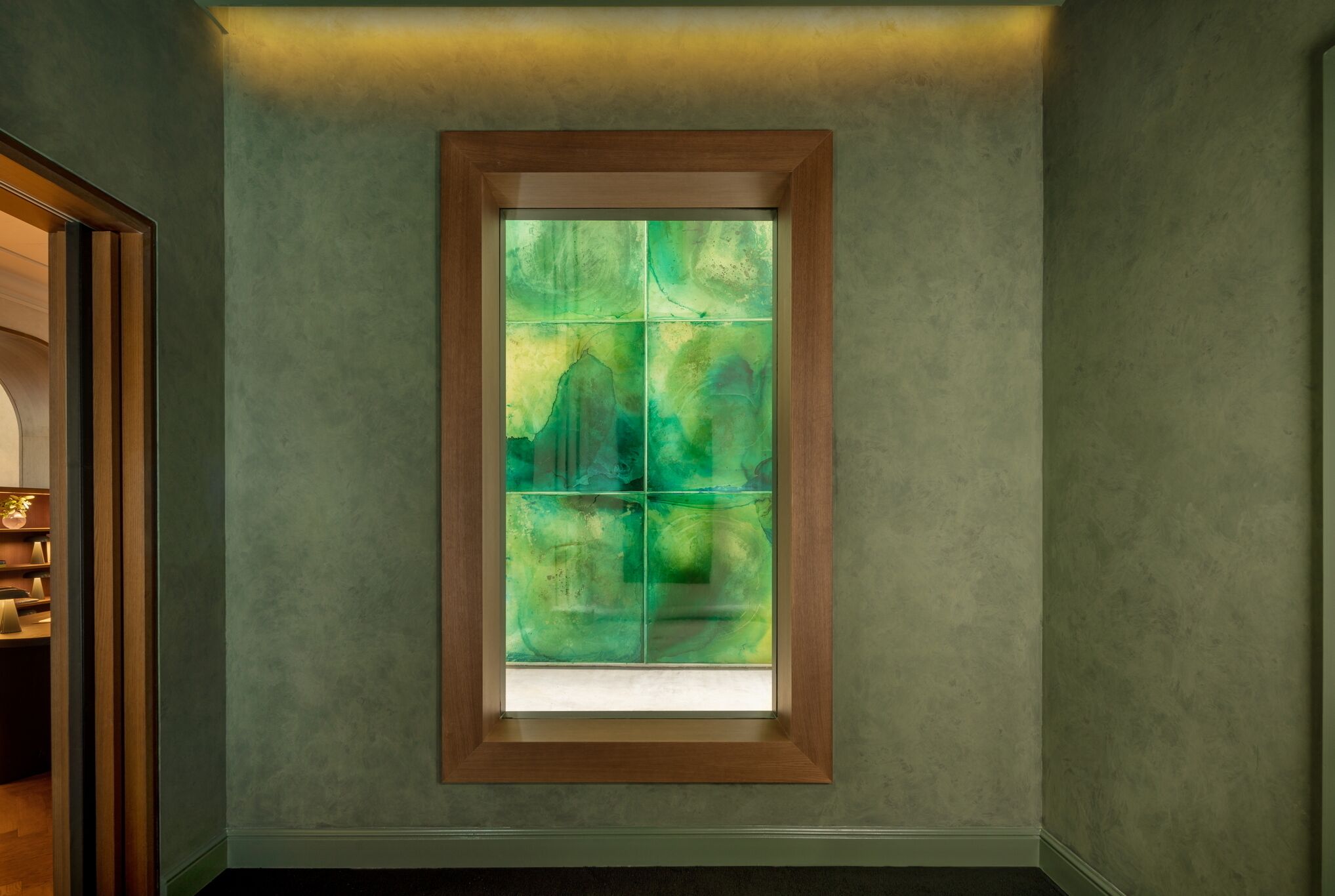 A room with a large window featuring a green abstract design.