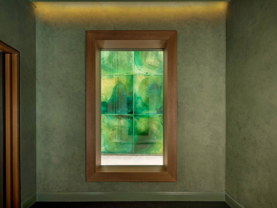 A room with a large window featuring a green abstract design.