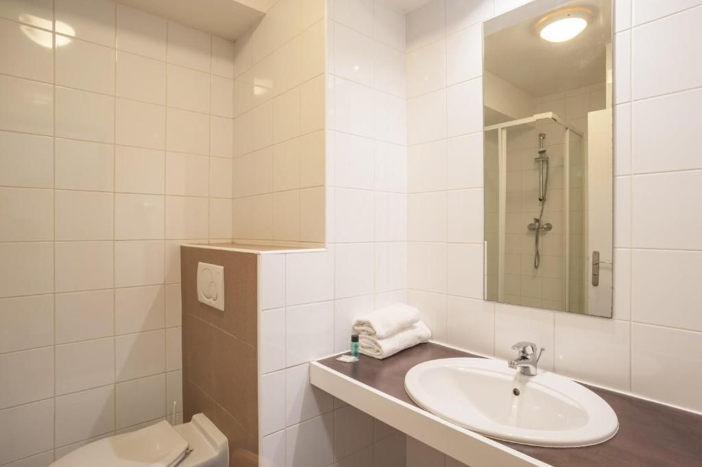 A bathroom with a white sink, a mirror, and a shower.