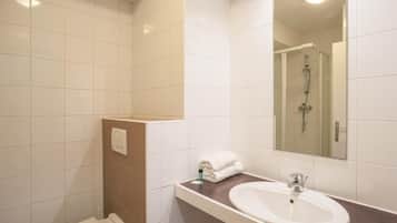 Un bagno con un lavandino bianco, uno specchio e una doccia.
