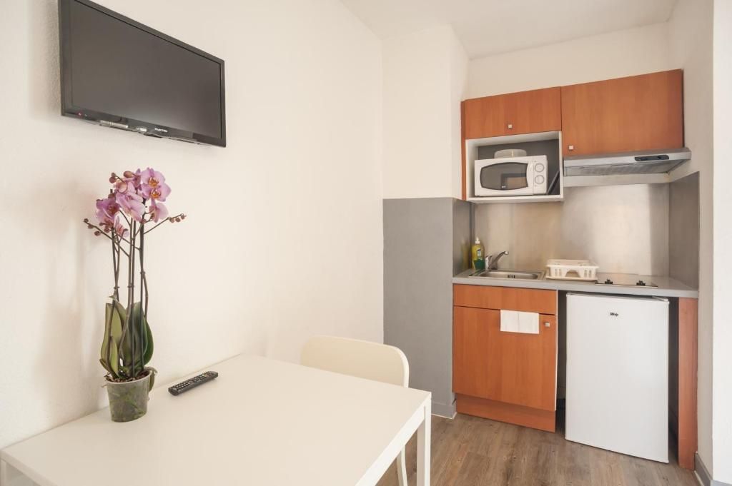 A compact kitchen with a microwave, a small refrigerator, and wooden cabinets.