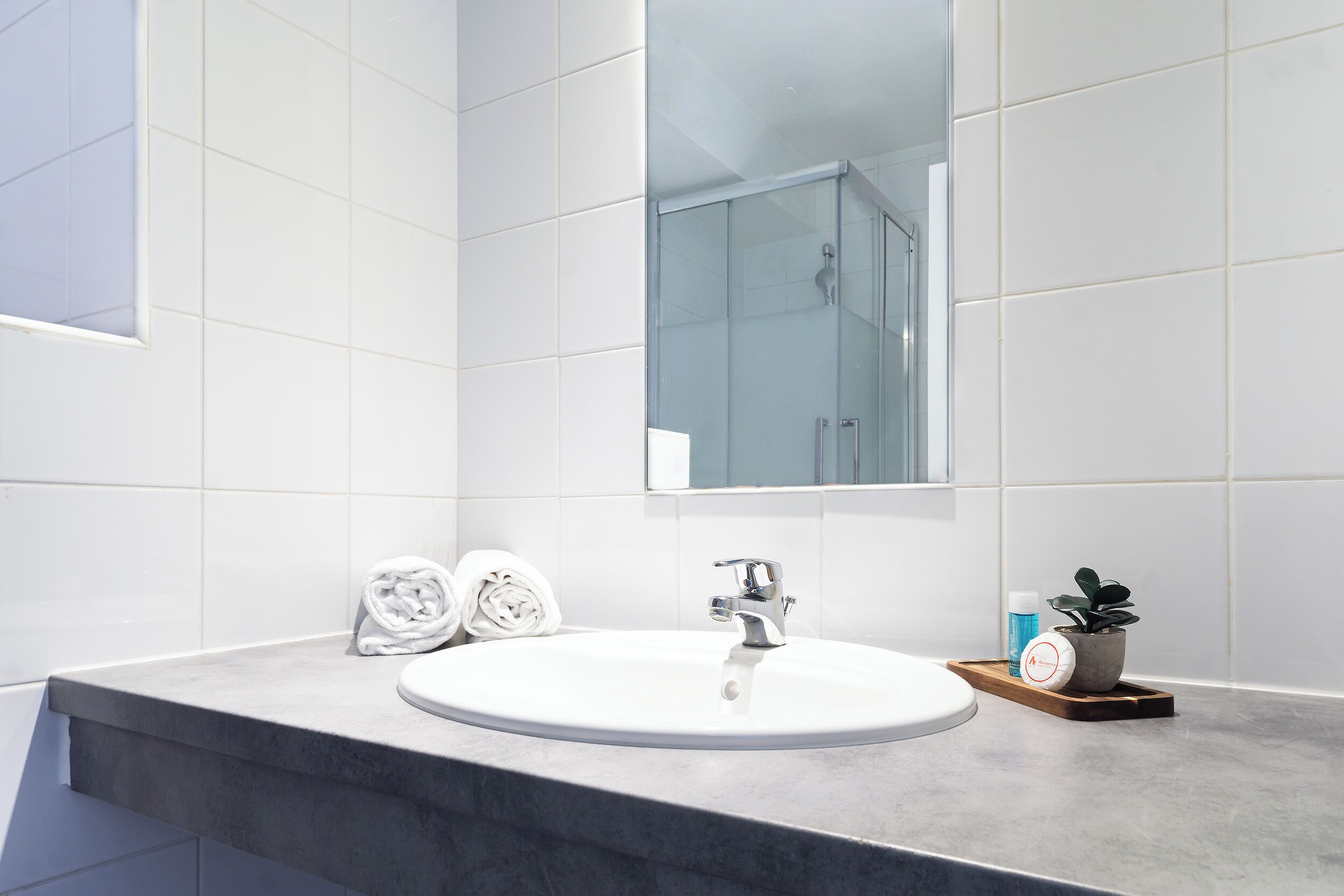 A bathroom with a white sink, a glass shower enclosure, and a mirror above the sink.