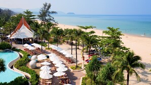 Um resort com piscina, área de praia e palmeiras.