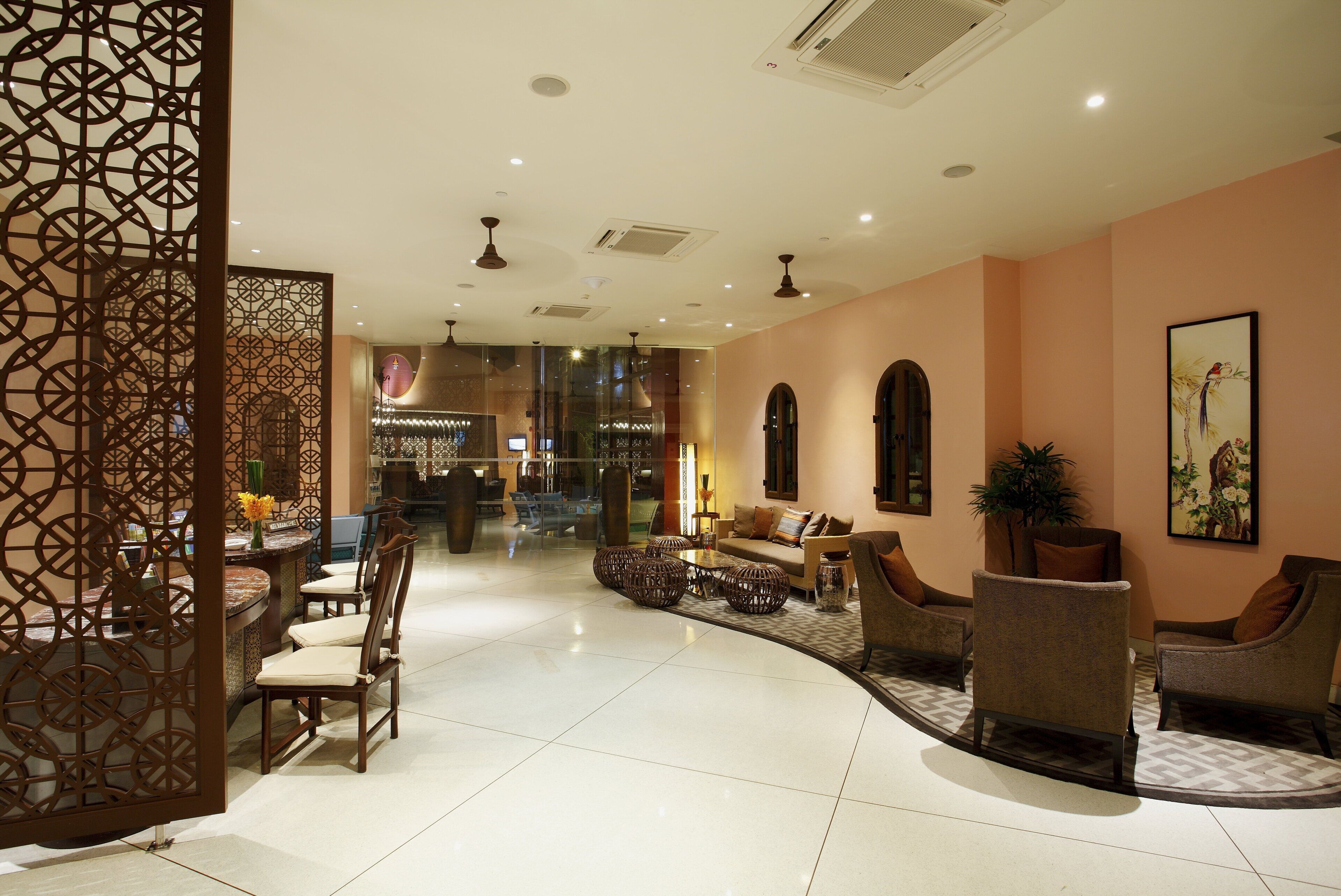 A hotel lobby with a reception desk, seating area, and a decorative partition.