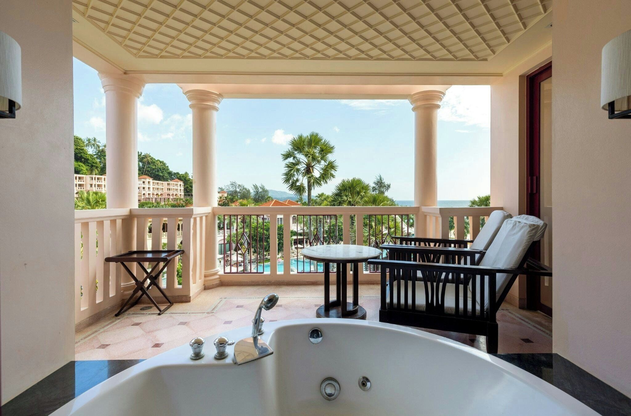 Un balcon avec une baignoire, une table et deux chaises.
