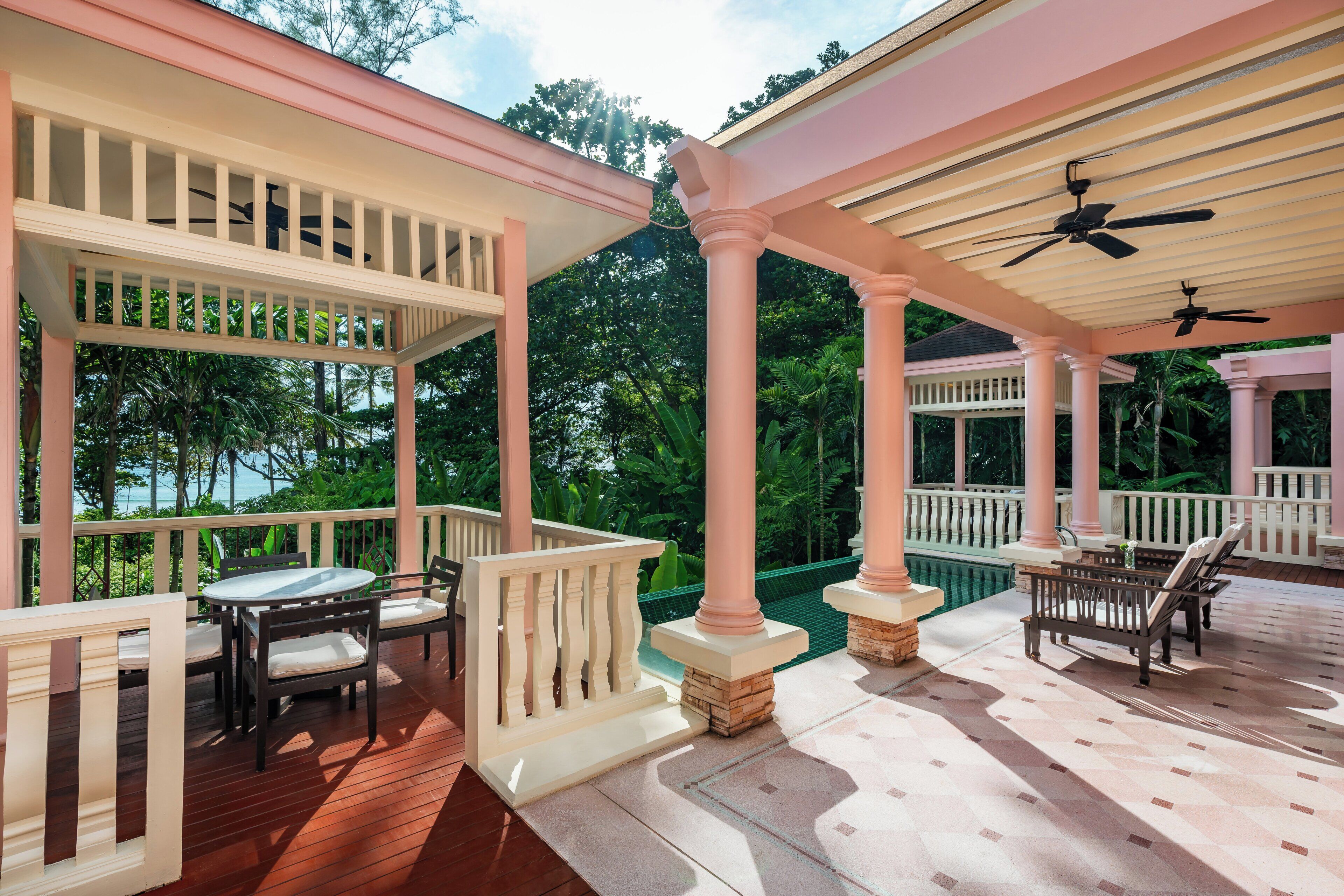 A covered outdoor area with a pool, wooden deck, and seating.