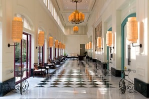 A hotel lobby with a checkered floor, seating areas, and wall-mounted lamps. - Centara Grand Beach Resort Phuket (Karon)