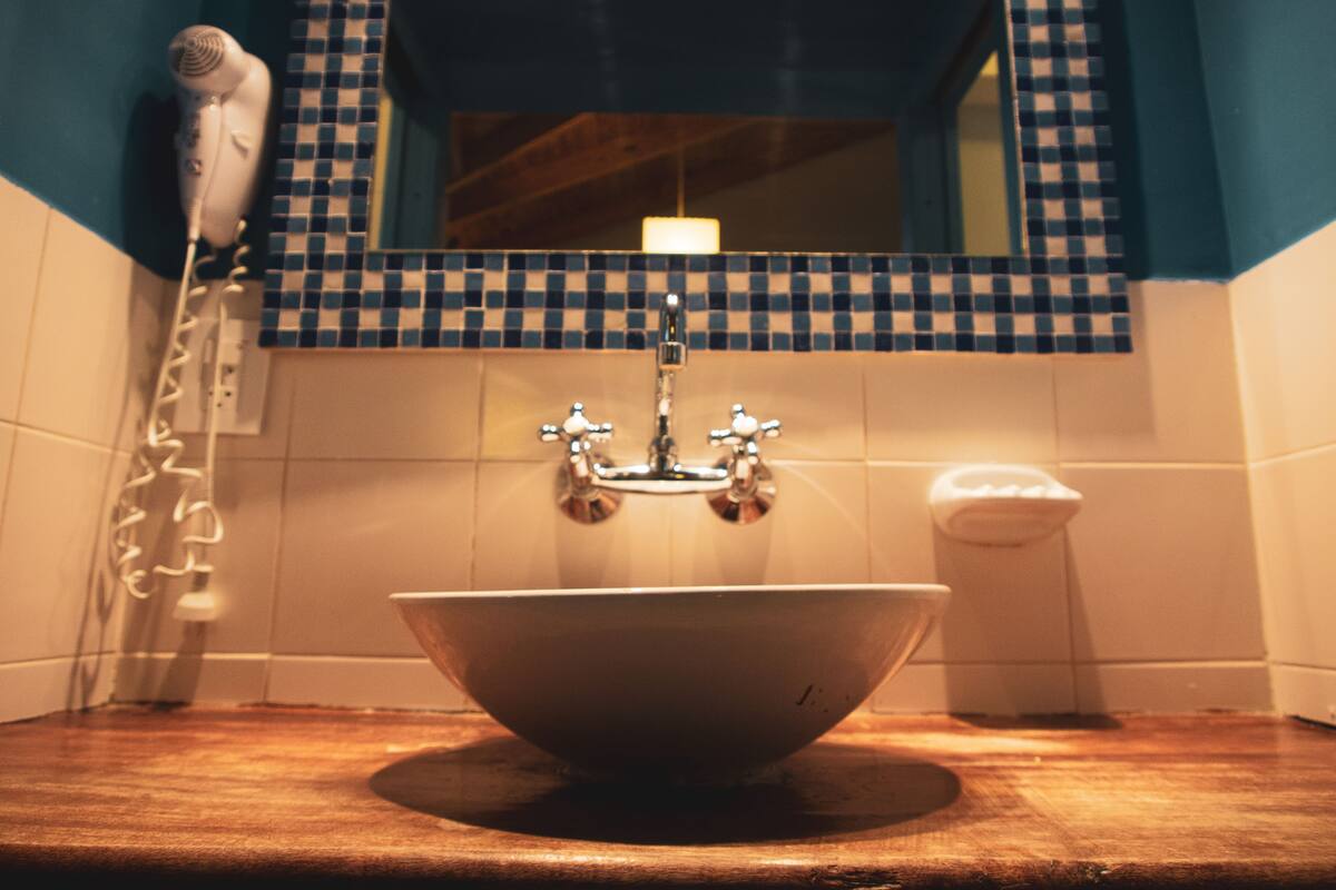 Ein Badezimmer mit einem weißen Waschbecken, einem Spiegel darüber und einer blau gefliesten Wand.