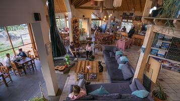 A spacious indoor area with a large sofa, dining tables, and a bar area.