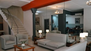 A spacious living room with a staircase, a sofa, armchairs, and a coffee table. - Hotel Alpino (Buenos Aires)