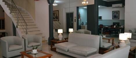 Un salón espacioso con una escalera, un sofá, sillones y una mesa de centro.