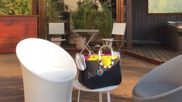A deck with a white chair, a black bag with a keychain, and a hot tub.