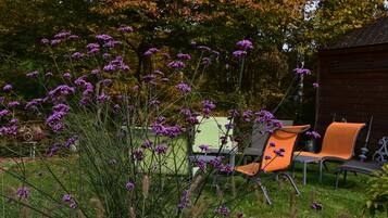 Un jardín con flores púrpuras y mobiliario exterior.