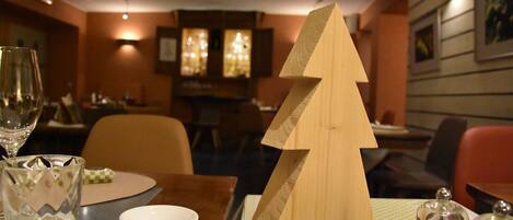 Una mesa de comedor con un centro de mesa navideño de madera, una copa y un bol.