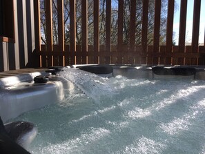 A hot tub area with wooden railings and a view of trees in the background.