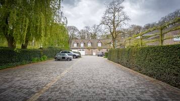 Un camino pavimentado que conduce a una casa de fachada de ladrillo y tejado de tejas.