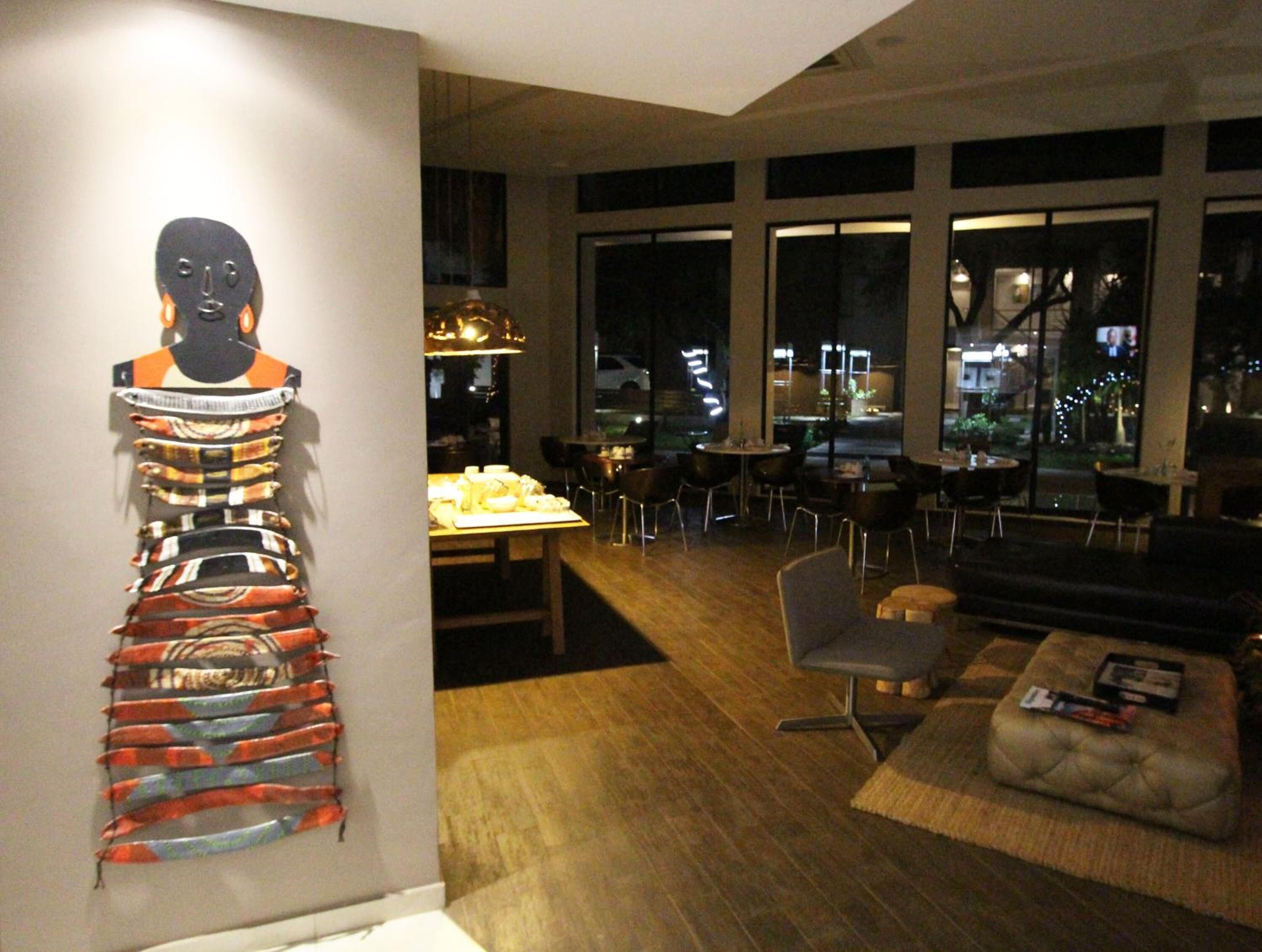 A modern interior with a dining area, large windows, and a unique wall art piece.