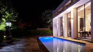 A modern house with a swimming pool, large windows, and a well-lit patio area. - The Lakes Boutique Lodge (Pretoria)