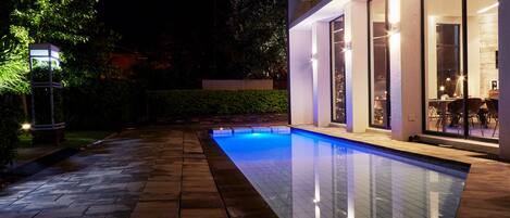 Una casa moderna con piscina, ventanas amplias y un patio luminoso.
