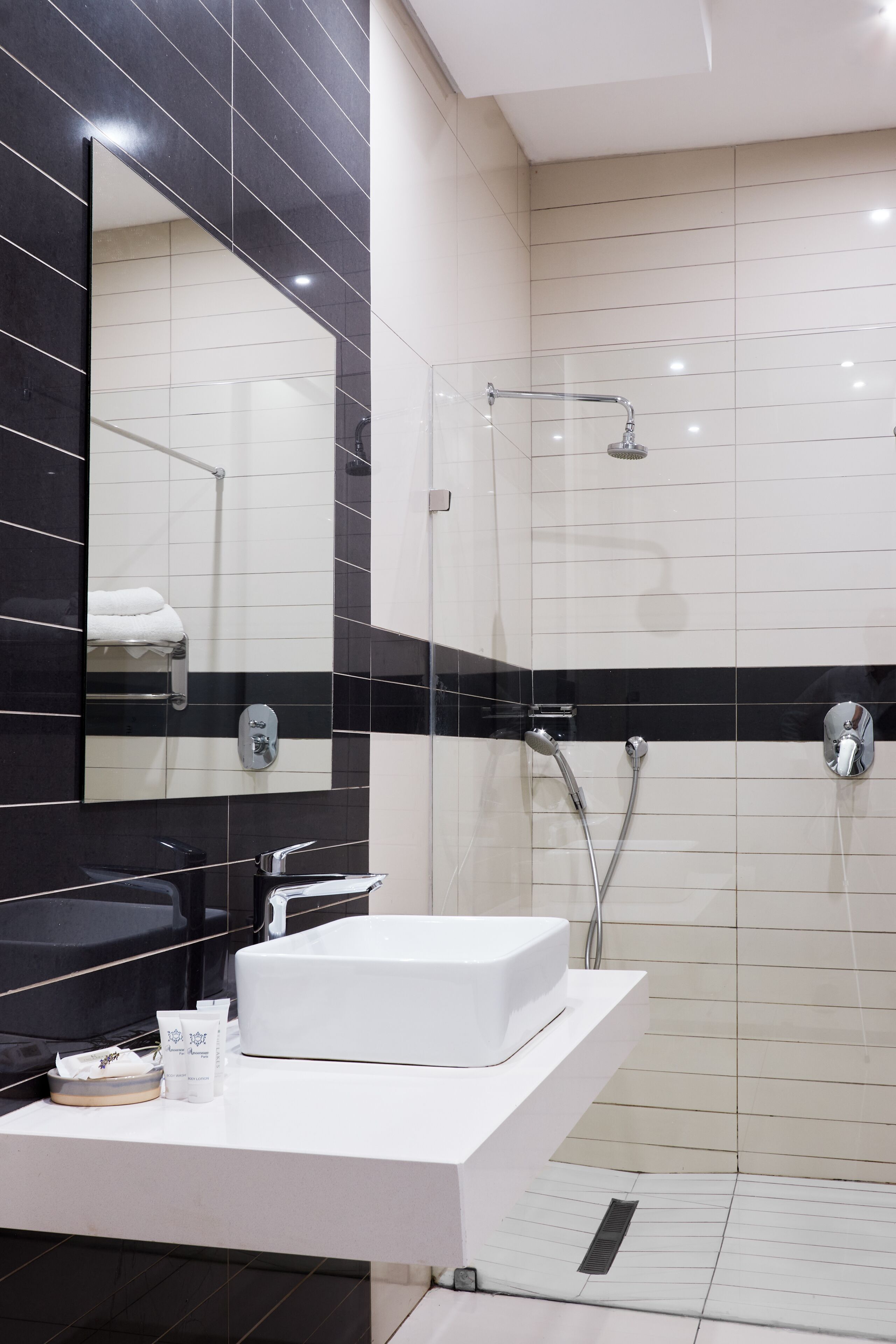 A modern bathroom with a white sink, a large mirror, and a glass-enclosed shower area.