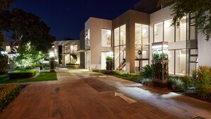 A modern building with large windows, a well-lit entrance, and a paved walkway. - The Lakes Boutique Lodge (Pretoria)