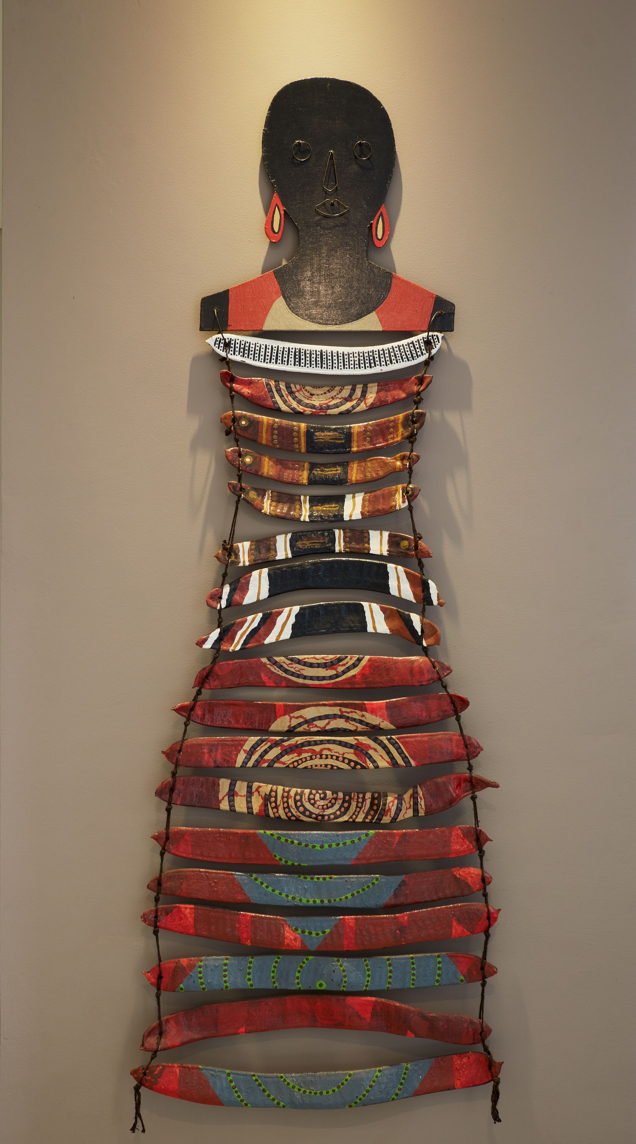 A wall-mounted sculpture with a human head silhouette and a patterned, layered design.
