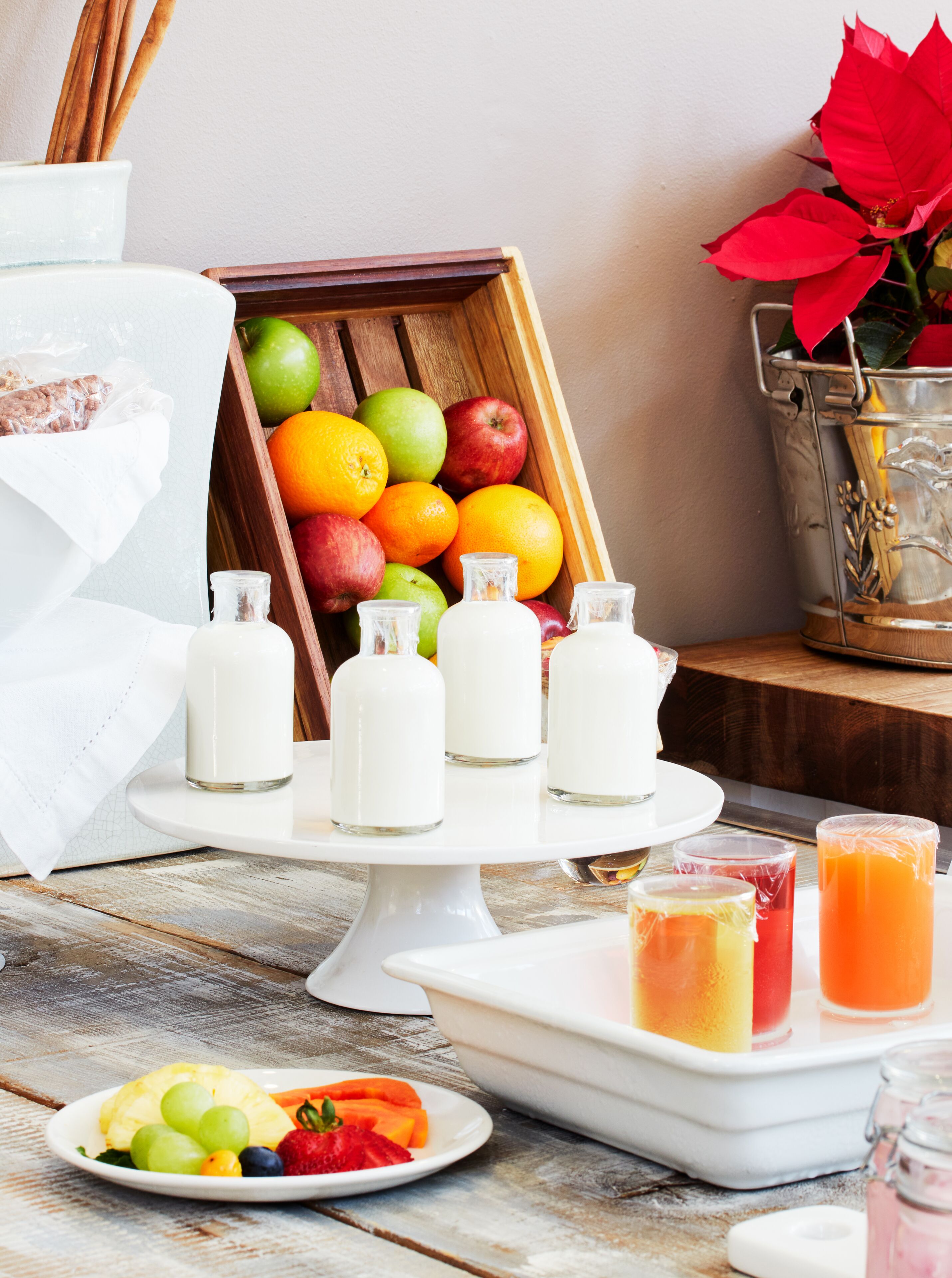 A breakfast setting with a fruit display, milk bottles, and a plate of fruit.
