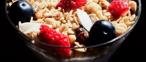 A bowl of cereal with strawberries, blueberries, and almonds.