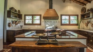 A kitchen with a central island, wooden cabinets, and a chimney.