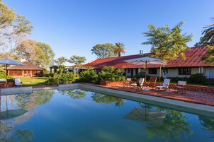 Una piscina al aire libre, sombrillas, sillones reclinables de piscina