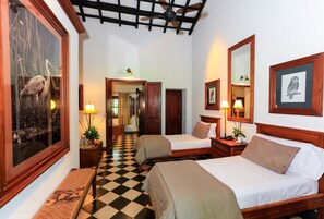 Habitación de hotel con dos camas, piso a cuadros, muebles de madera y cuadros en las paredes.