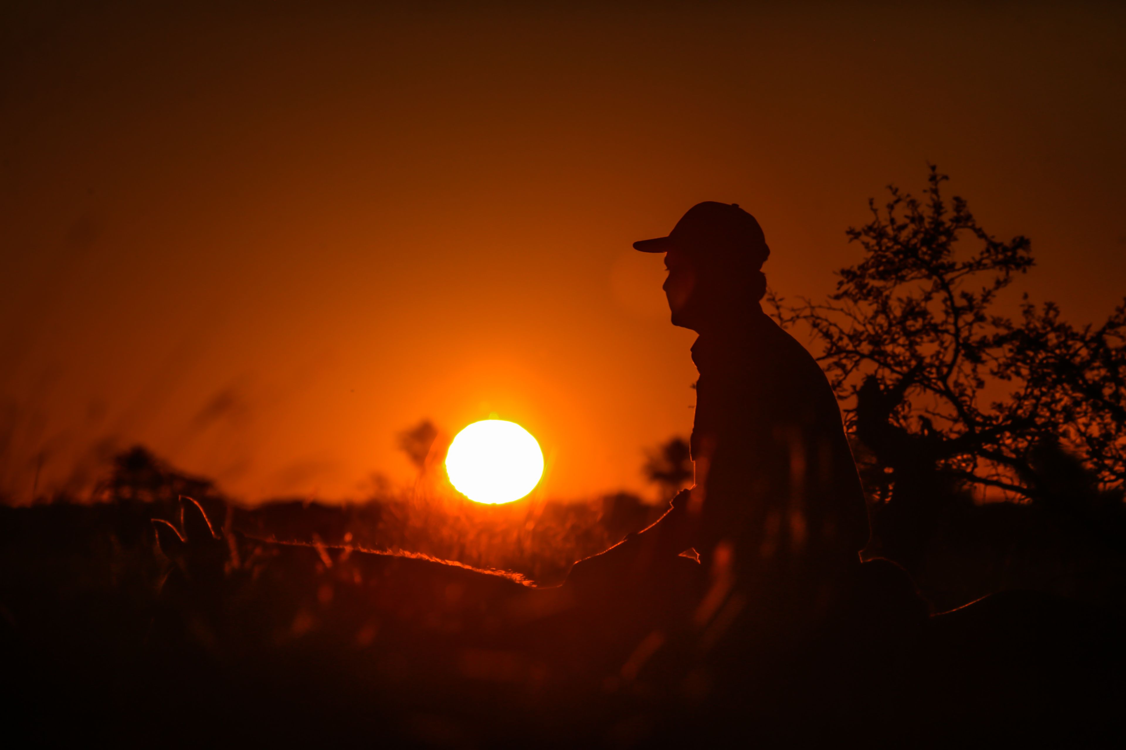 Silhouet van een persoon voor een ondergaande zon.