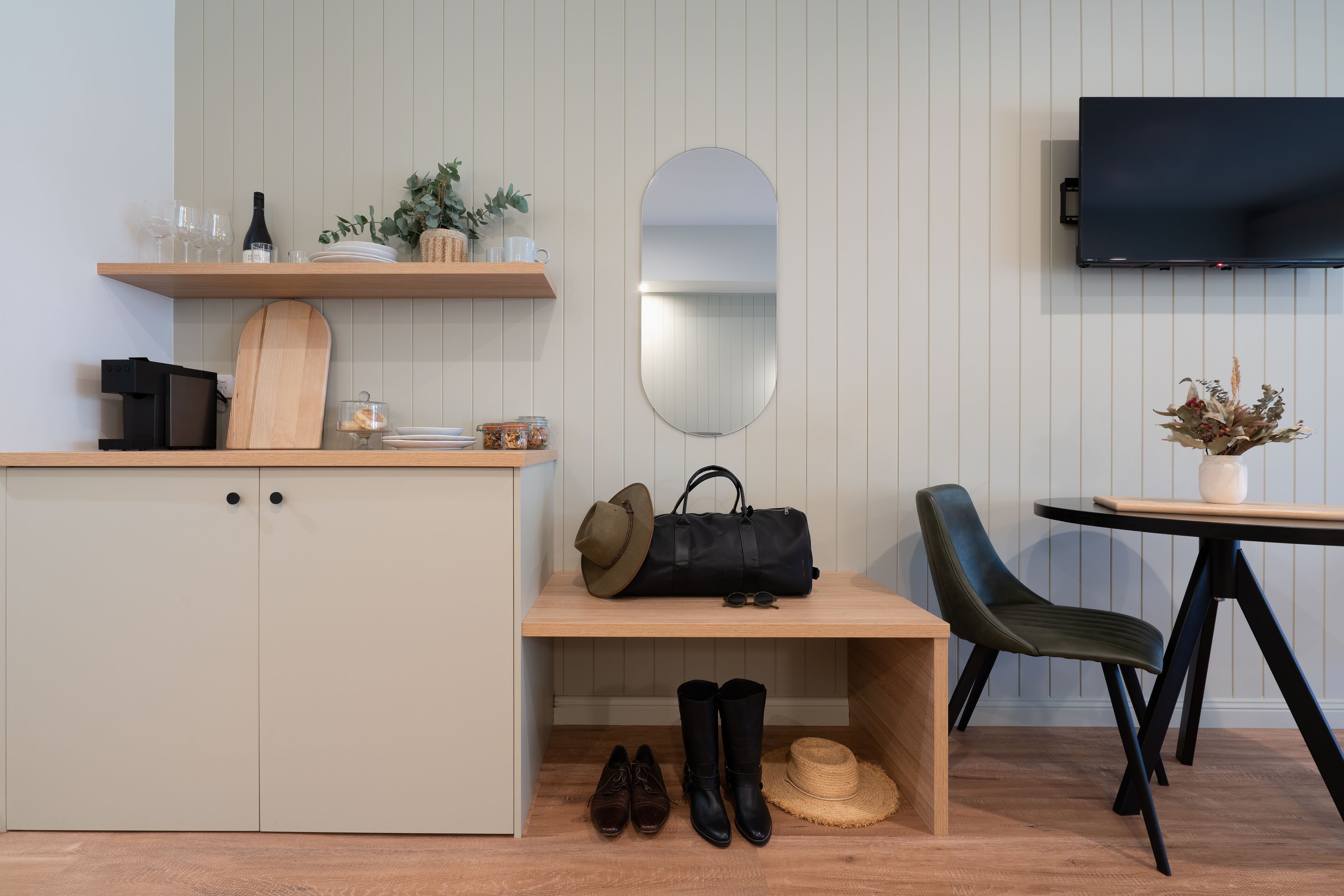 Una habitación moderna con un escritorio de madera, un espejo, un televisor y una silla.