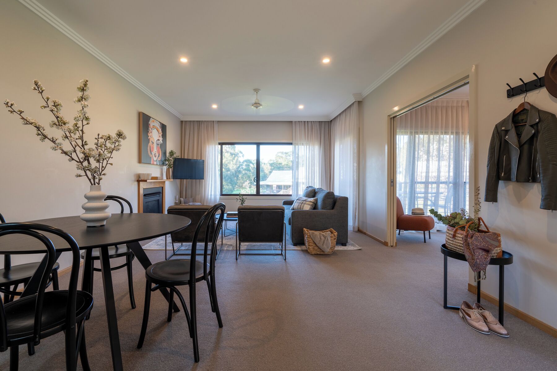 A modern living room with a dining area, a sofa, a TV, and a coat rack.