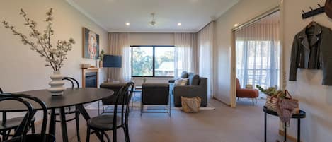 A modern living room with a dining area, a sofa, a TV, and a coat rack.