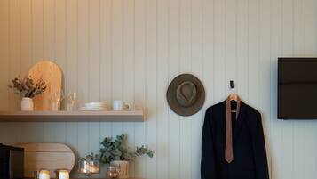 A neatly organized room with a wooden cabinet, a bench, a coat rack, and a television mounted on the wall.